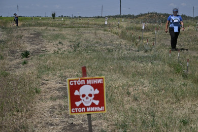 พื้นที่ทางการเกษตรแห่งหนึ่งในยูเครน ซึ่งเต็มไปด้วยกับดักระเบิด จนทางการติดป้ายแจ้งเตือนว่าเป็นพื้นที่อันตราย (Photo : AFP)