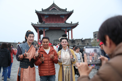 วันที่ 8 มีนาคม นักท่องเที่ยวไทยถ่ายภาพที่ระลึกกับนักแสดงสวมบท "ก๊วยเจ๋ง-อึ้งย้ง" จากเรื่องมังกรหยก บนกำแพงเมืองเซียงหยางอายุ 2,800 ปี มณฑลหูเป่ย